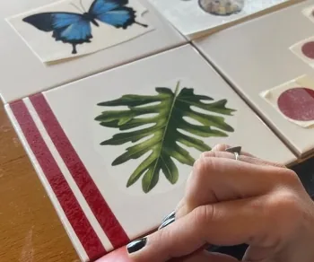 Mão pintando folha em azulejo