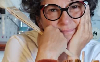 Mulher sorridente com óculos em pose pensativa e acolhedora